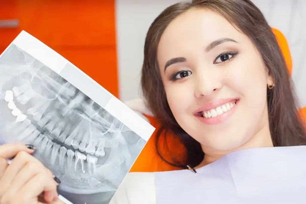 Patient holding x-ray of teeth while laying in dental chair.